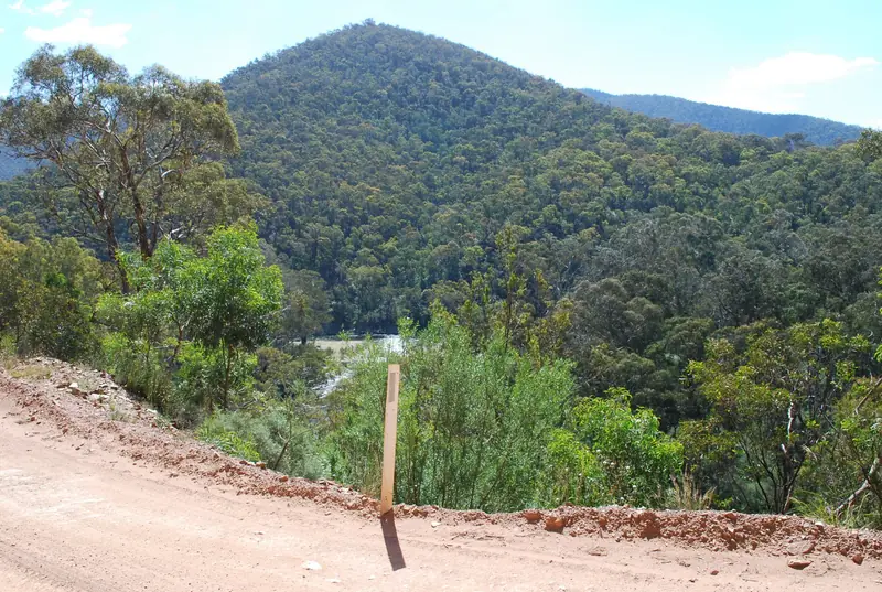 A gravel road with a view across bush covered mountains