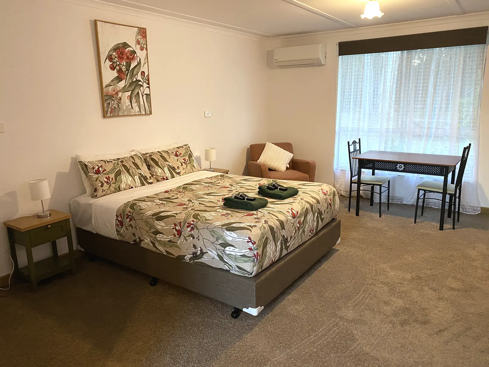 Refurbished motel room with queen bed, armchair and dining table