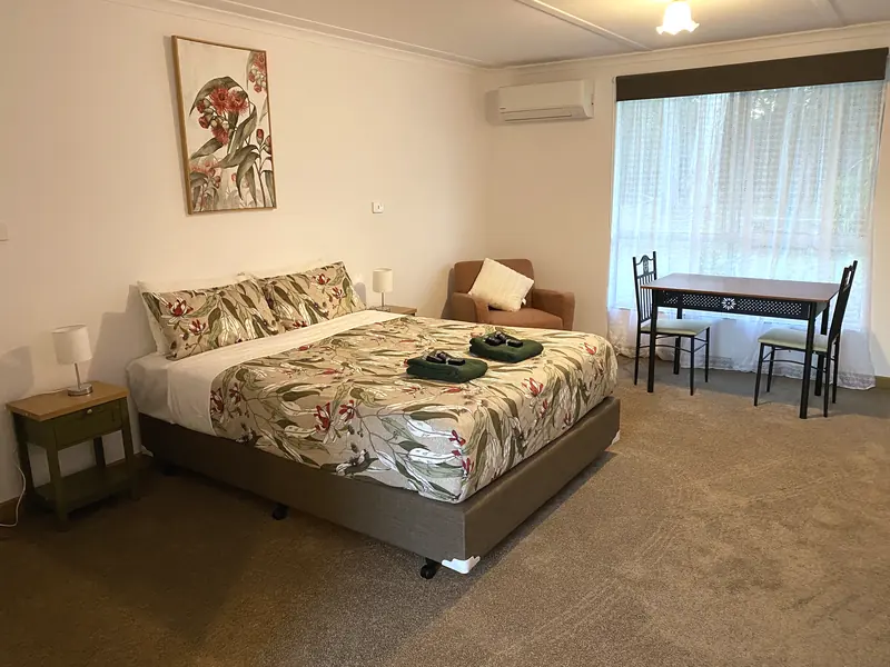 Refurbished motel room with queen bed, armchair and dining table
